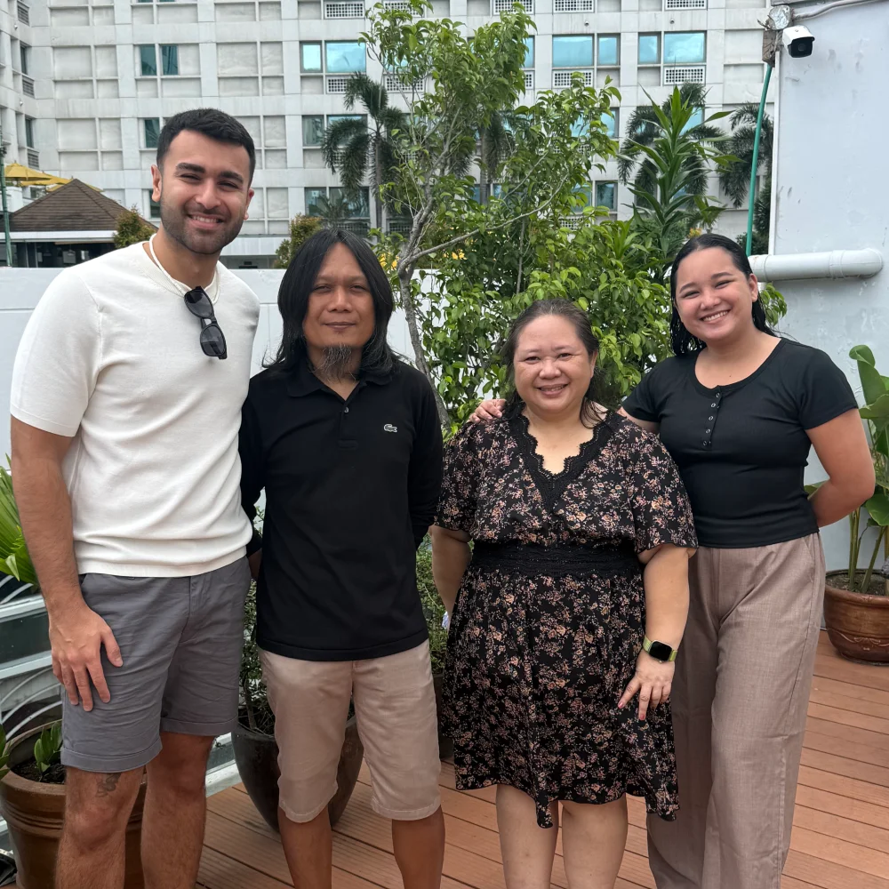 Louis Riat-Bonello, in a white T-shirt, standing on a rooftop terrace with three members of the Optisearch team, two women and a man, all smiling