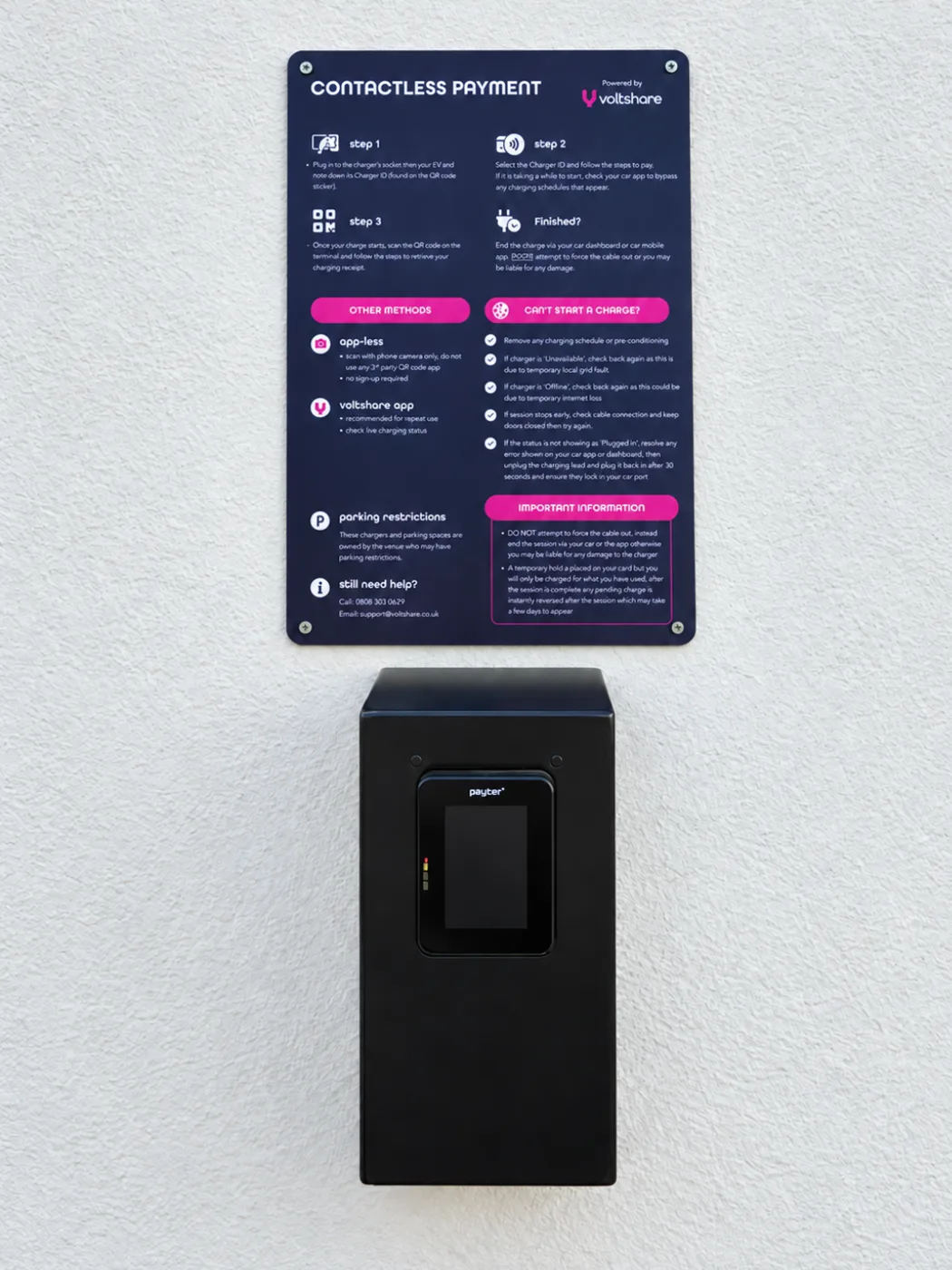 A contactless payment terminal mounted on a white wall beneath a navy and pink voltshare sign with step-by-step payment instructions